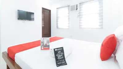 a white bedroom with a bed with a sign on it at RedDoorz Plus at DBuilders Poblacion BGC in Manila