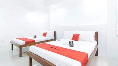 two beds in a room with white walls and red pillows at RedDoorz Plus at DBuilders Poblacion BGC in Manila