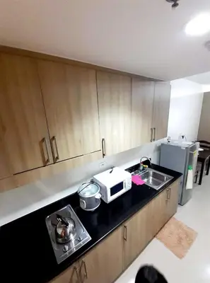 a kitchen with a sink and a microwave at Shore 1 Residences,MOA Complex - One Bedroom Apartment in Manila