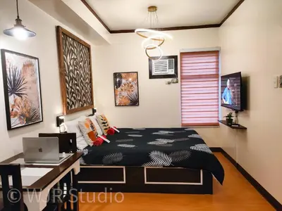 a bedroom with a bed and a desk with a laptop at Queen Bed Deluxe- Contemporary Style in Manila
