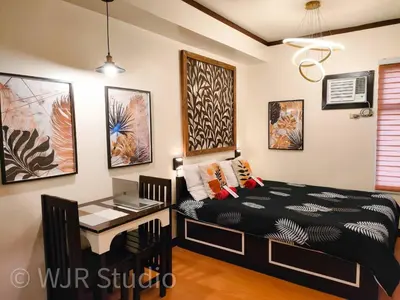 a bedroom with a bed and a table with a desk at Queen Bed Deluxe- Contemporary Style in Manila
