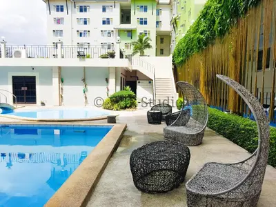 a pool with chairs next to a building at Queen Bed Deluxe- Contemporary Style in Manila