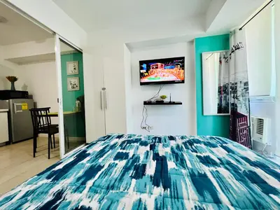 a bedroom with a bed and a tv on the wall at Azure Positano Tower Beach Vibe in Manila