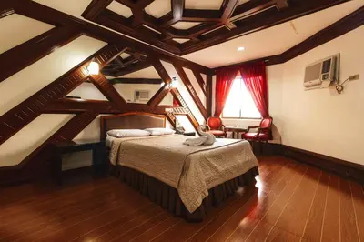 a bedroom with a bed in a room with wooden ceilings at Town and Country Hotel V Mapa in Manila
