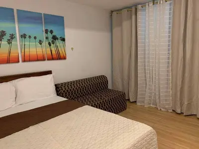 a bedroom with a bed and a couch and a window at AZURE A6 beachpool with Balcony Wifi near mall airport in Manila