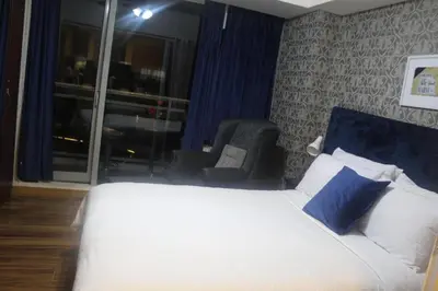 a bedroom with a bed and a chair and a window at AZURE A6 beachpool with Balcony Wifi near mall airport in Manila