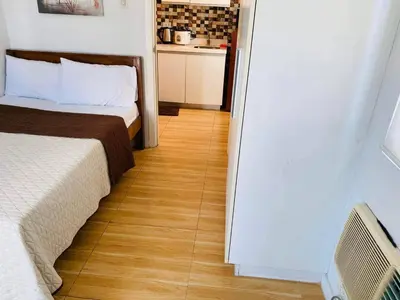 a bedroom with two beds and a wooden floor at AZURE A6 beachpool with Balcony Wifi near mall airport in Manila