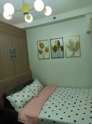 a bed in a bedroom with pictures on the wall at MOA Shore 2 1BR with Balcony WiFi Netflix Pool 4Pax in Manila