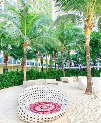 a white bench in a courtyard with palm trees at S-a-f-e Haven Resort Staycation in Manila