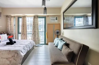 a bedroom with a bed and a couch and a mirror at Studio at Newport World Airport Area Prime Location in Manila