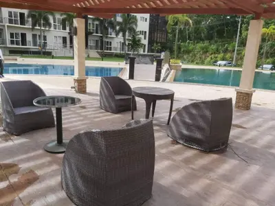 a patio with chairs and tables next to a pool at Affordable Tagaytay Monteluce 2 BR with Pool G28 in Silang