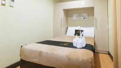a hotel room with a bed with two white towels on it at 153 Silverio Suites Paranaque City in Manila