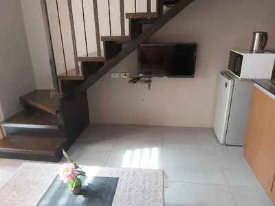 a living room with a staircase and a television at Affordable Tagaytay Monteluce 2 BR Loft with pool 32 in Lalaan Primero