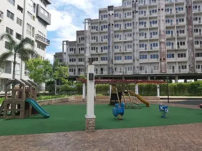 a playground in front of a large building at Affordable Tagaytay Monteluce 2 BR Loft with pool 32 in Lalaan Primero