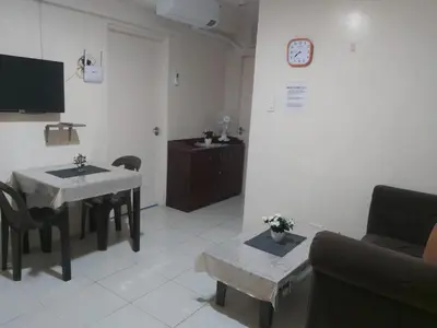 a living room with a table and a clock on the wall at Affordable Tagaytay Monteluce 1BR with Pool G10 in Lalaan Primero