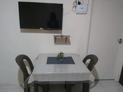a table with two chairs and a television on a wall at Affordable Tagaytay Monteluce 1BR with Pool G10 in Lalaan Primero