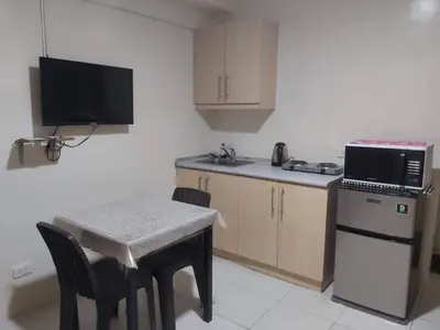 a small kitchen with a small table and a microwave at Affordable Tagaytay Monteluce 1 BR WITH POOL-224 in Lalaan Primero