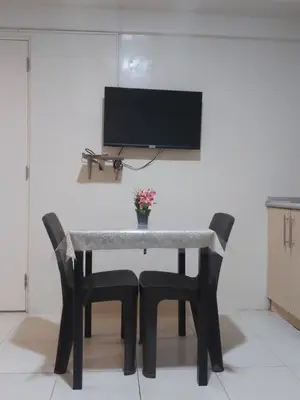a table with two chairs and a tv on a wall at Affordable Tagaytay Monteluce 1 BR WITH POOL-224 in Lalaan Primero