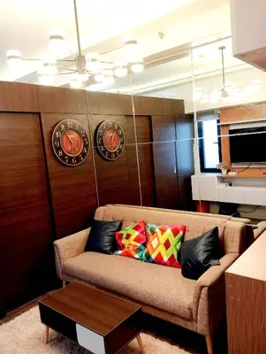 a living room with a couch and clocks on the wall at Air Residences Makati Condo Elegant Grand Hotel Type in Manila