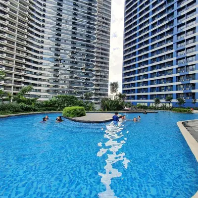 a group of people in a swimming pool with tall buildings at Air Residences Makati Condo Elegant Grand Hotel Type in Manila