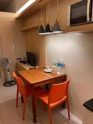 a kitchen with a wooden table and orange chairs at Netflix- Destina Stays at Jazz Residences Makati, MetroManila in Manila