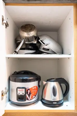 a cabinet filled with pots and pans and a toaster at Shell Residences Pasay 1BR Walk to MOA Newly Renovated! in Manila