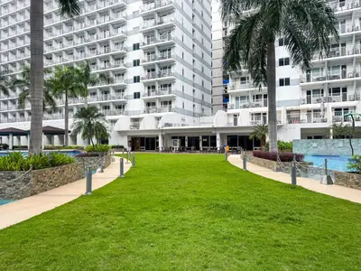 a park in front of a large apartment building at Shell Residences Pasay 1BR Walk to MOA Newly Renovated! in Manila