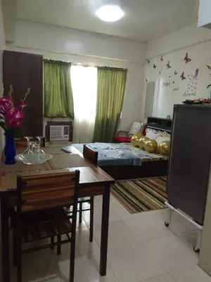 a living room with a bed and a dining room table at Aliyahs Place in Cainta