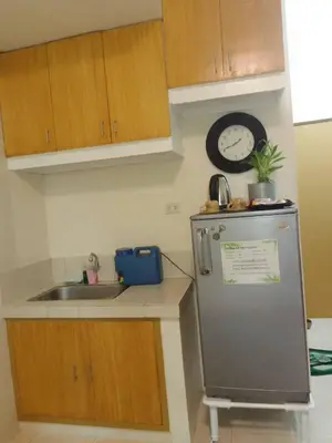 a kitchen with a sink and a refrigerator and a clock at Aliyahs Place in Cainta