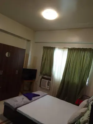 a bedroom with a bed and a window with curtains at Aliyahs Place in Cainta