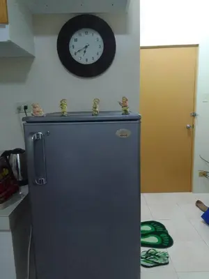 a clock on the wall above a refrigerator in a kitchen at Aliyahs Place in Cainta