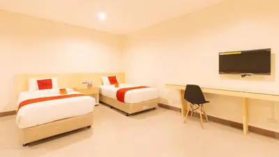 a room with two beds and a desk with a television at RedDoorz Plus @ Kaizen Suites Taft Avenue in Manila