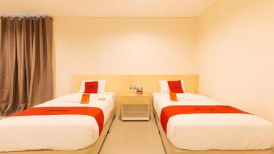 a bedroom with two beds with red and white sheets at RedDoorz Plus @ Kaizen Suites Taft Avenue in Manila
