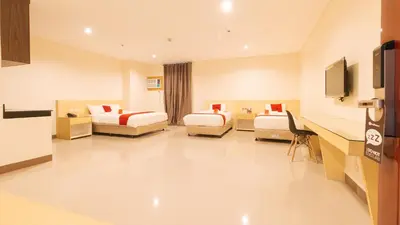 a hotel room with two beds and a desk at RedDoorz Plus @ Kaizen Suites Taft Avenue in Manila