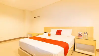 a bedroom with a large bed with a red pillow at RedDoorz Plus @ Kaizen Suites Taft Avenue in Manila