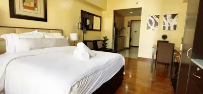 a bedroom with a large bed with white sheets at Mosaic Tower in Manila