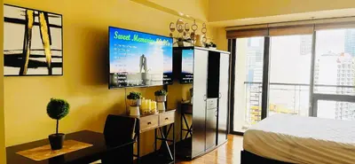 a bedroom with a desk and a tv on the wall at Mosaic Tower in Manila