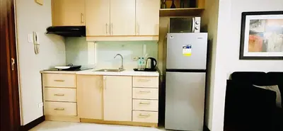 a kitchen with a white refrigerator and wooden cabinets at Mosaic Tower in Manila
