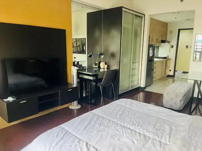 a bedroom with a bed and a desk and a television at Mosaic Tower in Manila
