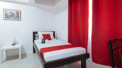 a small bedroom with a bed with red curtains at RedDoorz near UST Sampaloc Manila in Manila