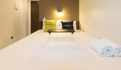 a white bed with a yellow and black pillows on it at UrbanView at San Antonios Place Sampaloc Manila in Manila