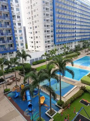 a view of a swimming pool with palm trees and buildings at Blue's Residences in Manila