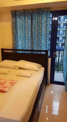 a bedroom with a bed and a window with curtains at Blue's Residences in Manila
