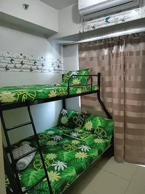 a bunk bed room with two bunk beds with green sheets at Blue's Residences in Manila