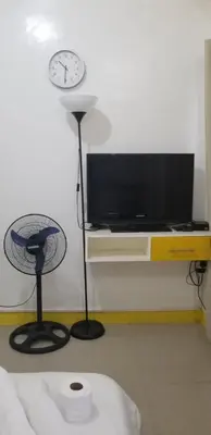 a room with a tv and a fan and a clock at Innsite Room Rentals in Manila