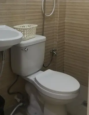 a bathroom with a white toilet and a sink at Innsite Room Rentals in Manila