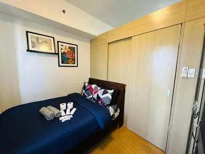 a bedroom with a blue bed with pillows at 1 Bedroom with balcony Near Airport Bgc Taguig City in Manila
