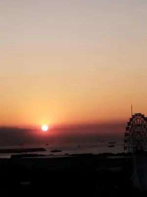 a sunset over the ocean with a ferris wheel at Schönes Apartment mit Pool-Nutzung in Manila