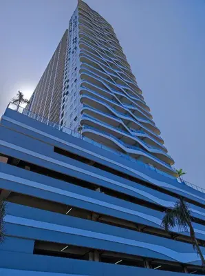 a tall blue building with palm trees in front of it at Schönes Apartment mit Pool-Nutzung in Manila