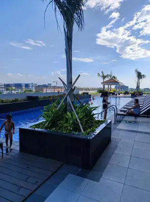 a palm tree in a planter next to a swimming pool at Schönes Apartment mit Pool-Nutzung in Manila